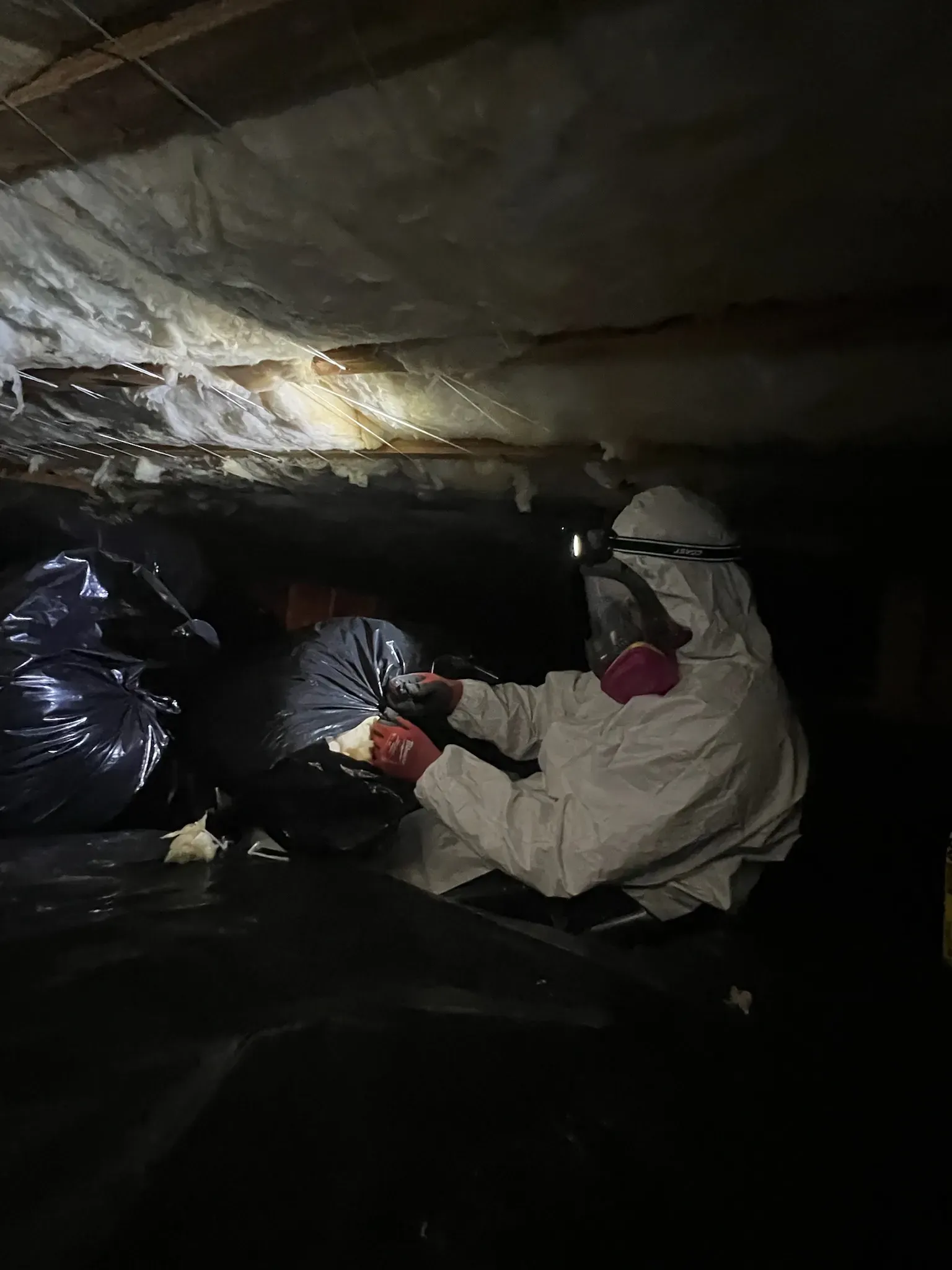worker on ppe putting insulation in trashbag